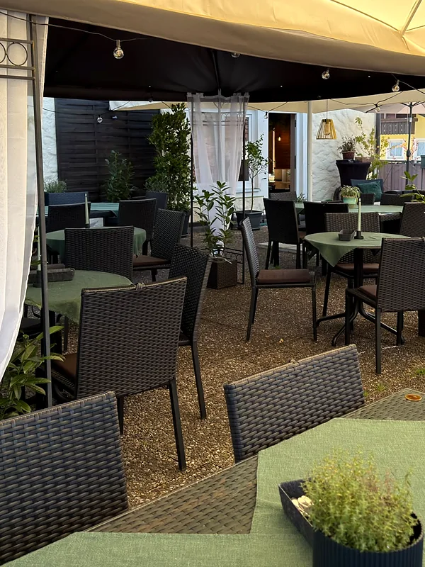 Sonnenterrasse bei Tag mit Pavillon, weißen Vorhängen und gedeckten Tischen